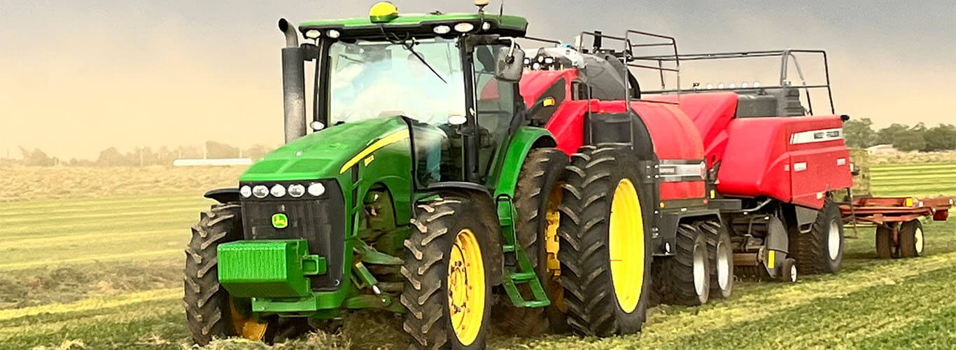 John Deere pulling a square baler and steamer.